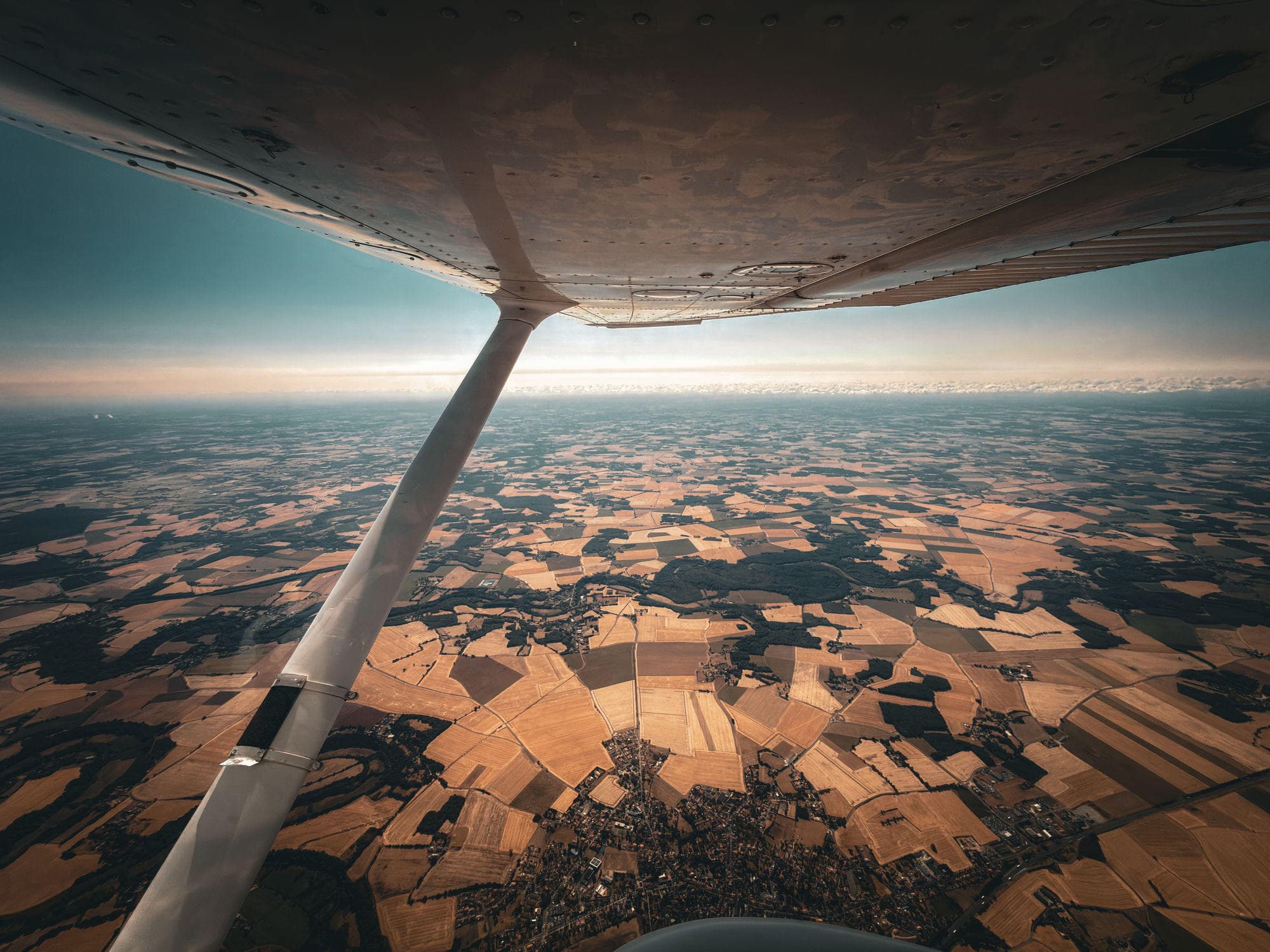 Vue depuis l'aile d'un Cessna en croisière au-dessus de la campagne girondine en fin de journée