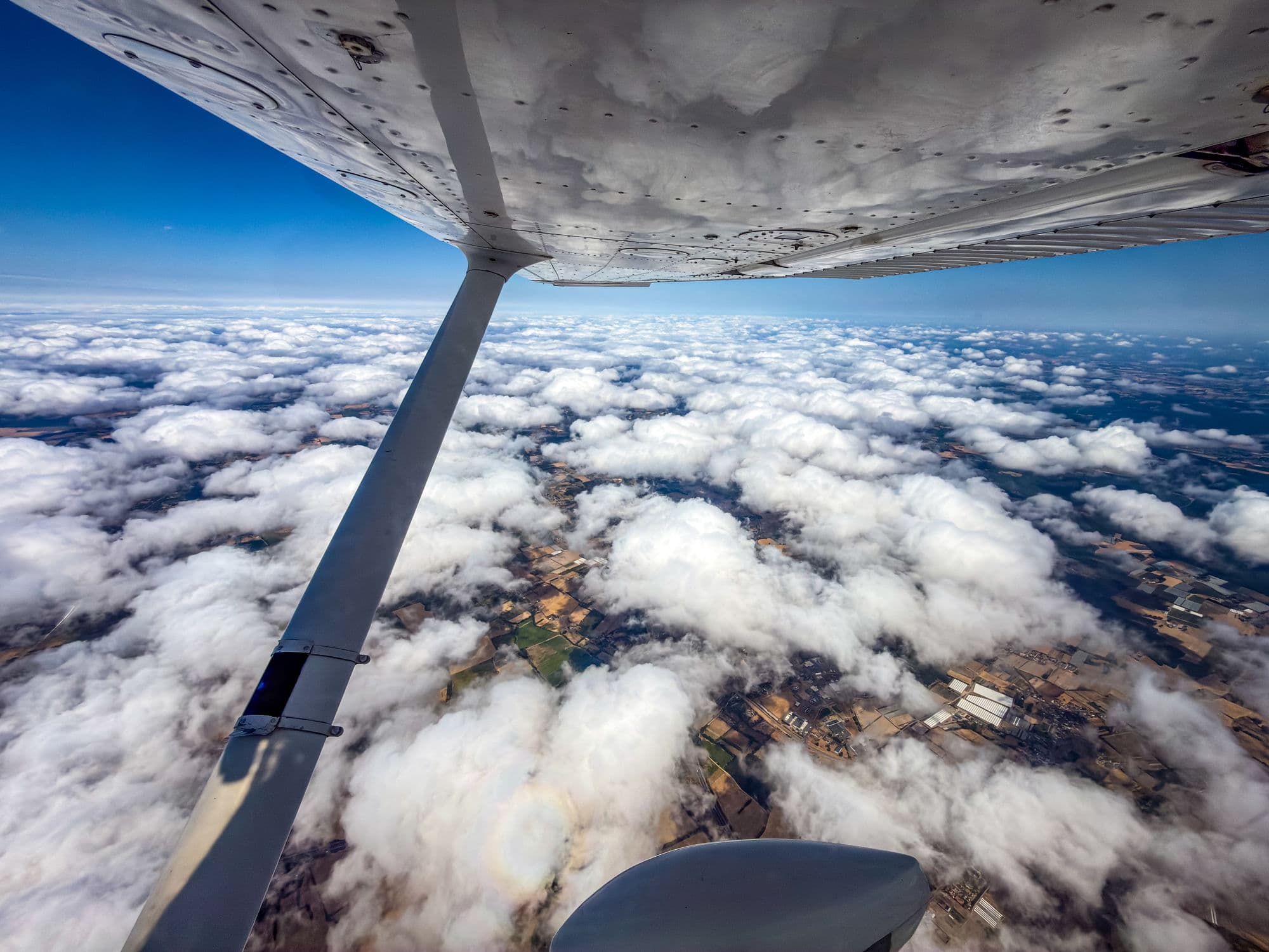 Aile d'un avion du club en croisière au-dessus d'un champ de cumulus