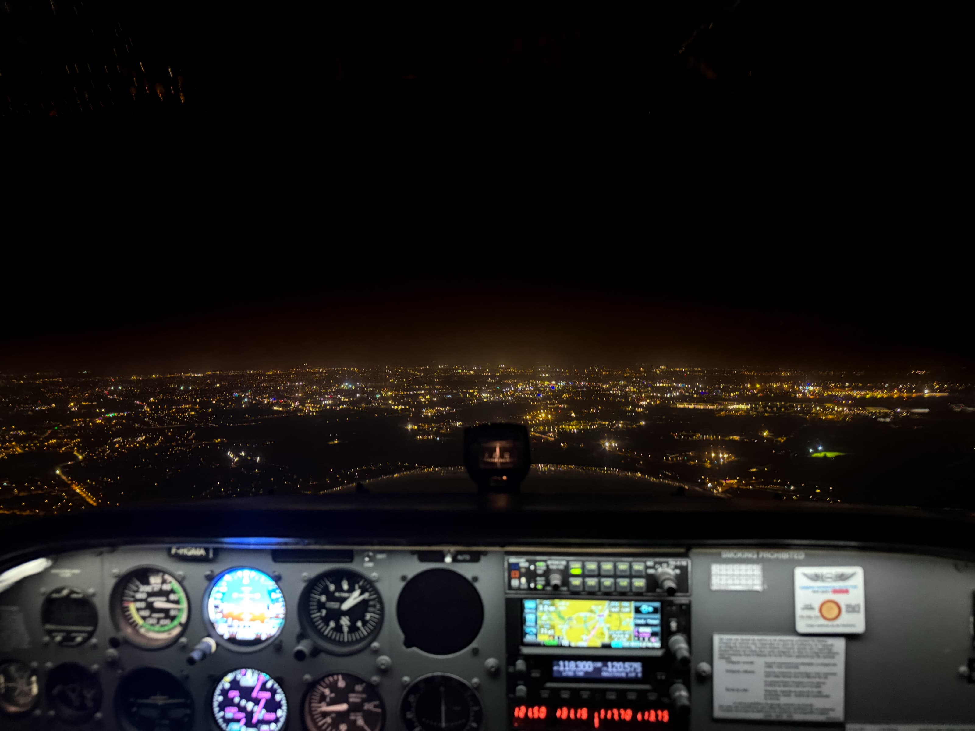 Approche de nuit aux commandes, ville illuminée à l'horizon