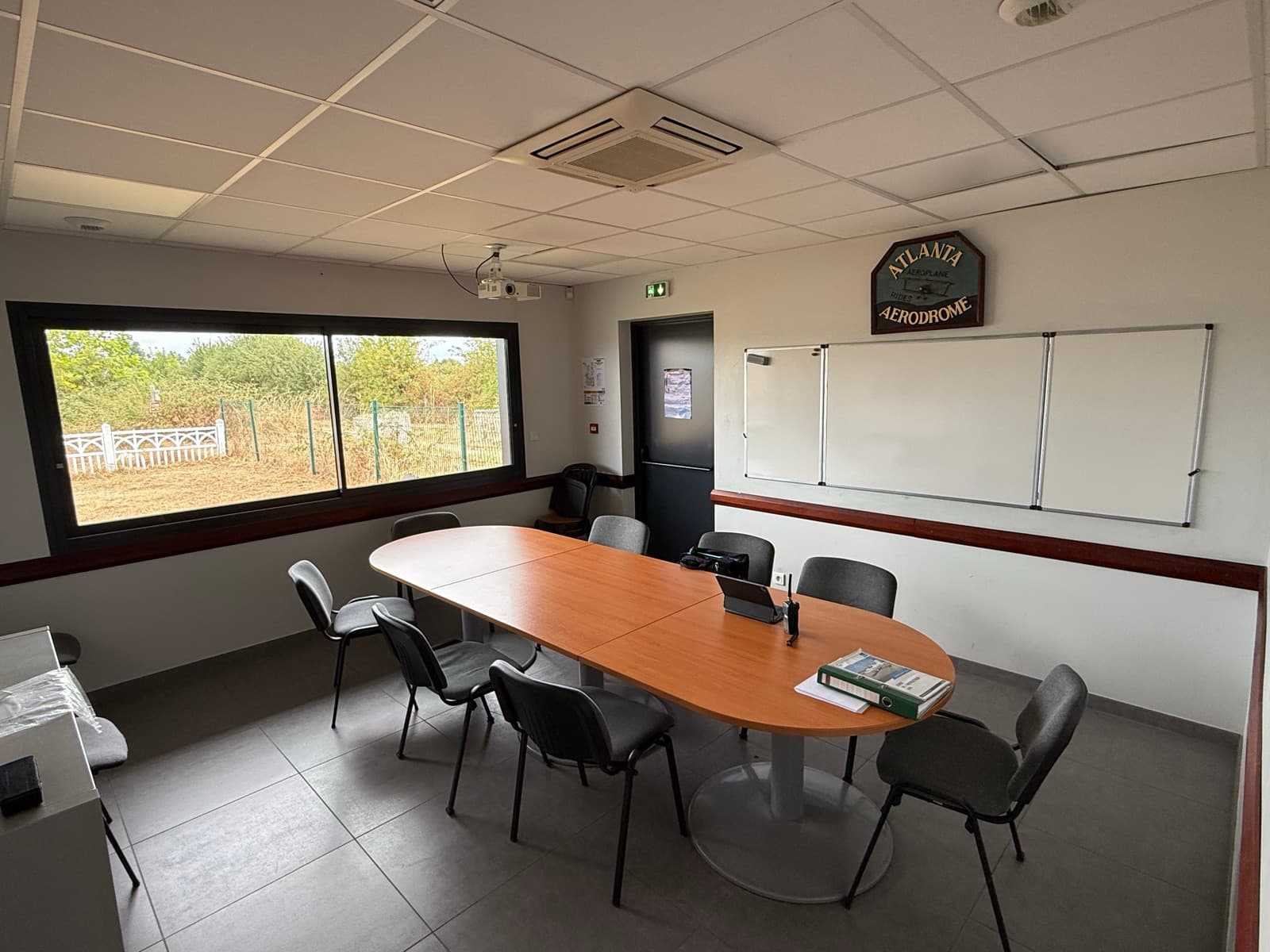 Salle de briefing du club-house avec table de réunion et tableau blanc